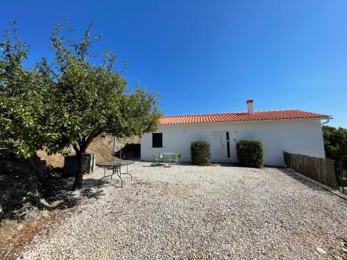 a white house with a table and a tree at Cottage Abrunheiro Grande in Vila de Rei