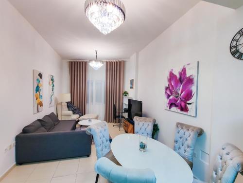 a living room with a couch and a table and chairs at Elegant Fresh 1BR with Heated Pool, just steps from Mall, Restaurants & Fitness center in Dubai