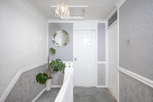 a hallway with a white door and a chandelier at Relaxing 3-Bedroom Retreat House Free Parking 8ppl in Ollerton