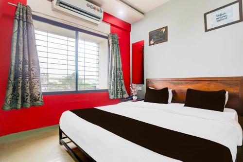 a bedroom with a large bed and a red wall at Collection O Wardha Road Near Airport in Nagpur