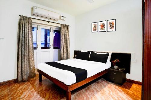 a bedroom with a bed with white sheets and black pillows at Hotel O Holiday Street Calangute formerly Shruti Resort in Goa