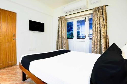a bedroom with a white bed and a window at Hotel O Holiday Street Calangute formerly Shruti Resort in Goa
