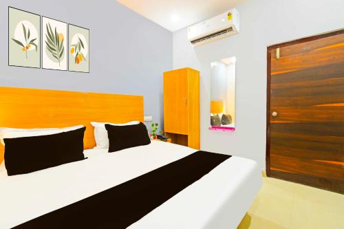1 dormitorio con 1 cama blanca grande y cabecero de madera en Hotel O Medipally, en Hyderabad