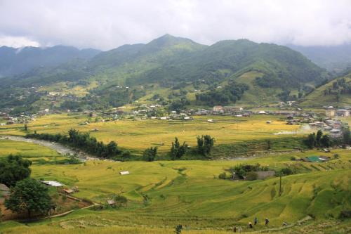 a village in a valley with mountains in the background at SaPa Big Tree Hmong Homestay in Sa Pa