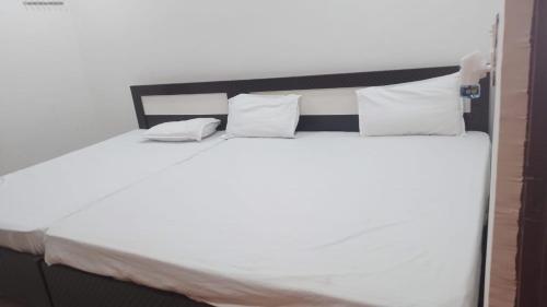 a bed with white sheets and pillows at Sri Govind restaurant and guest house in Ayodhya