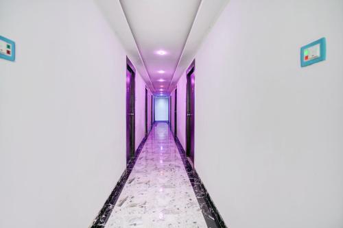 a corridor in a white building with purple lights at HOTEL O HAPPY PLACE HOTEL & RESORT in Gaya