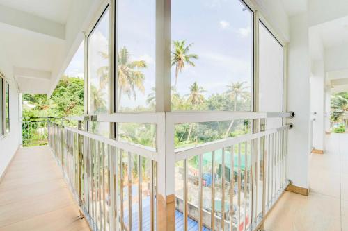 a room with large windows and a balcony with palm trees at Hotel O Valiyavila Junction in Trivandrum