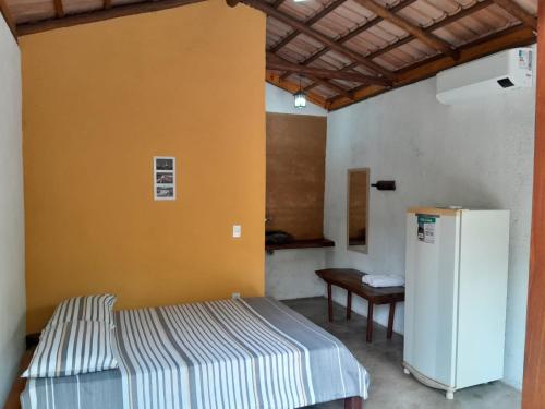 a room with a bed and a refrigerator in it at Chalés Santo Verde 2 in Goiás