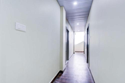 a hallway with white walls and a wooden floor at Hotel O Srisailam Highway in Shamshabad