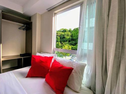 ジョアンペソアにあるJoao Pessoa Cabo Branco - Flat Vista Mar- 418- Green Sunset com piscina frente marの窓際のベッド(赤い枕2つ付)