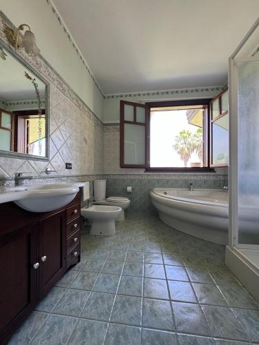 a bathroom with two sinks and a tub and two toilets at Villa esclusiva con piscina privata e vista Etna in Zafferana Etnea