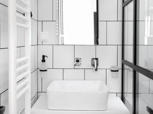 a white bathroom with a sink and a window at Athens View Loft - 02 in Athens