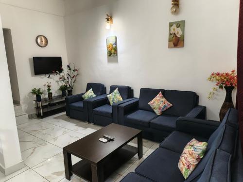 a living room with blue couches and a coffee table at Paloma Hotel Ring Road in Accra