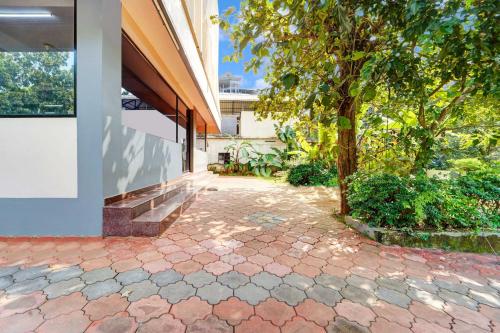a tree on a brick walkway next to a building at Collection O Thrissur Near Thrissur Medical College in Thekkumkara