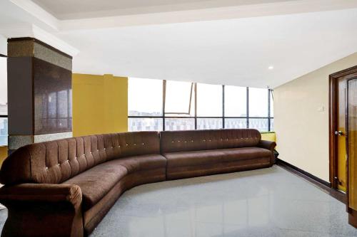 a brown leather couch in a room with windows at Collection O Padmavathi Puram Near Railway Station in Tirupati