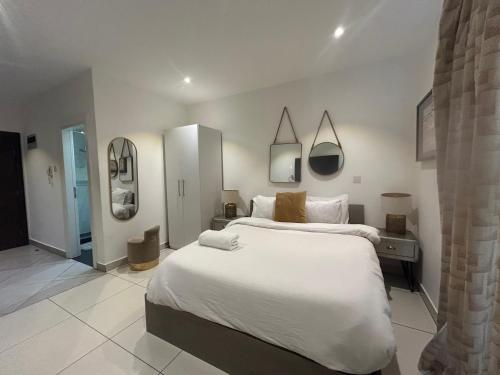 a large white bedroom with a large bed and mirrors at APARTMENTS GH - Accra - Cantonments - Embassy Gardens in Accra