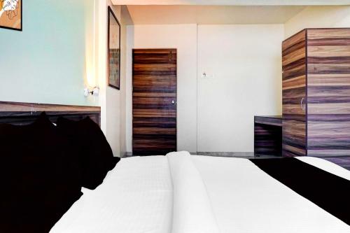 a bedroom with a white bed and a wooden closet at Collection O Ambegaon Road Katraj White Castle in Māngvādi