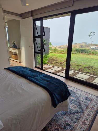 a bedroom with a bed and a large window at Modern Luxury Beach Villa in Ballito