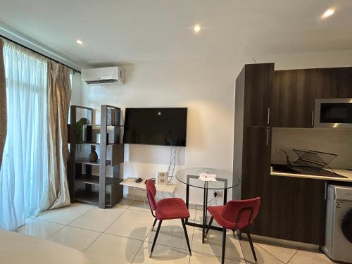 a living room with a table and two red chairs at APARTMENTS GH - Accra - Cantonments - Embassy Gardens in Accra