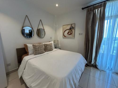 a bedroom with a white bed and a window at APARTMENTS GH - Accra - Cantonments - Embassy Gardens in Accra