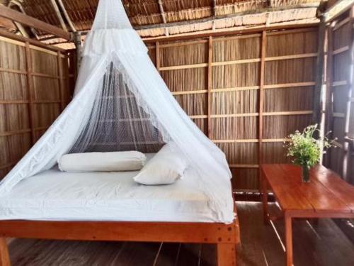 a bed with a net in a room with a table at Merpati homestay in Merpati