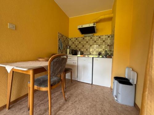 a kitchen with yellow walls and a table with a chair at Simplex Stays Hotel Lauer in Bad Soden-Salmünster