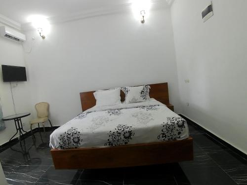 a bedroom with a bed with a black and white comforter at Jacobs Hôtel in Douala