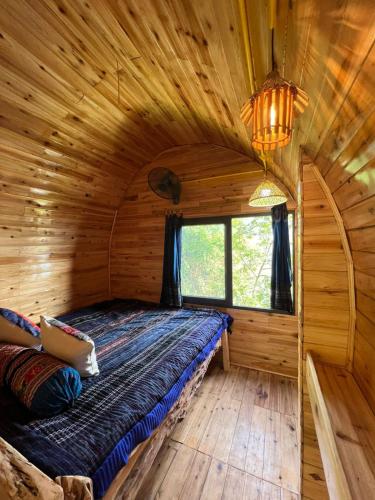 a bed in a log cabin with a window at SaPa Big Tree Hmong Homestay in Sa Pa