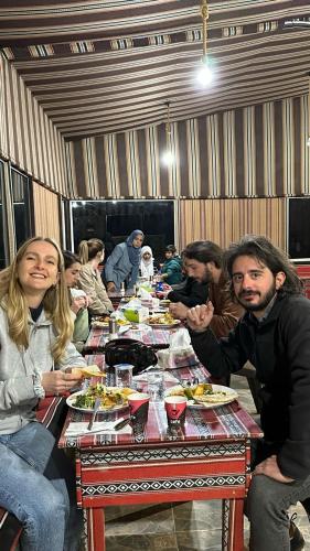 a group of people sitting at a table eating food at Wadi Rum Star Camp in Wadi Rum