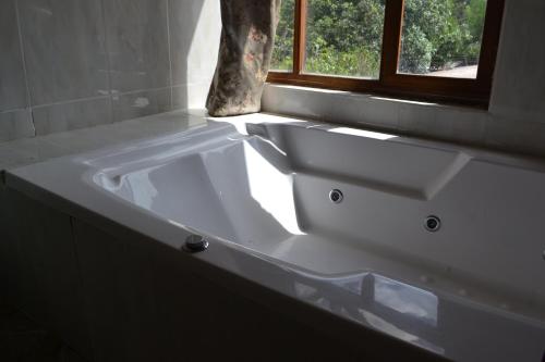 a white sink in a bathroom with a window at Bamboo Village Place in Tumbaco