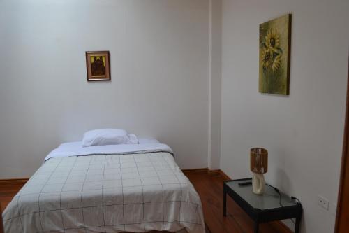 a white bedroom with a bed and a table at Bamboo Village Place in Tumbaco