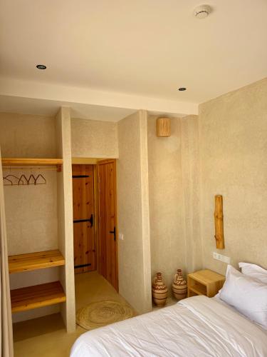 a bedroom with a bed and a wooden door at SURFHALLA Morocco in Imsouane