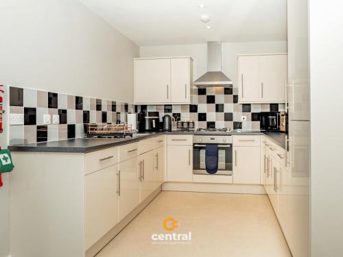 a kitchen with white cabinets and black and white tiles at CENTRAL SERVICED APARTMENTS - City Quay - 2 Bedrooms - En-Suite Bathroom - Dedicated Parking Space - Fully Equipped - Walk Away From Dundee Bus & Train Station - Close to City Centre with River Views and Balcony - NEW in Dundee