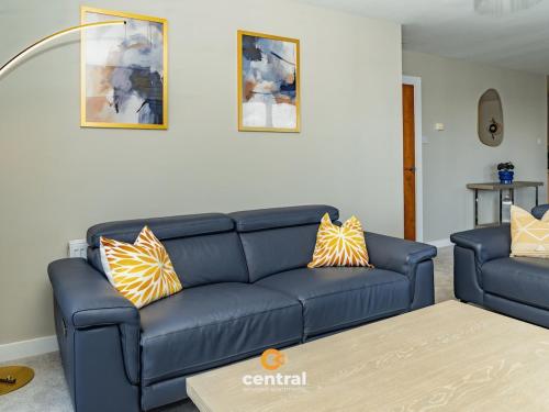 a living room with a blue couch and two pillows at CENTRAL SERVICED APARTMENTS - City Quay - 2 Bedrooms - En-Suite Bathroom - Dedicated Parking Space - Fully Equipped - Walk Away From Dundee Bus & Train Station - Close to City Centre with River Views and Balcony - NEW in Dundee