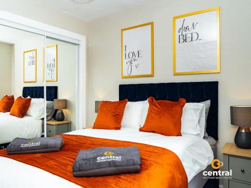 a bedroom with two beds with orange pillows at CENTRAL SERVICED APARTMENTS - City Quay - 2 Bedrooms - En-Suite Bathroom - Dedicated Parking Space - Fully Equipped - Walk Away From Dundee Bus & Train Station - Close to City Centre with River Views and Balcony - NEW in Dundee