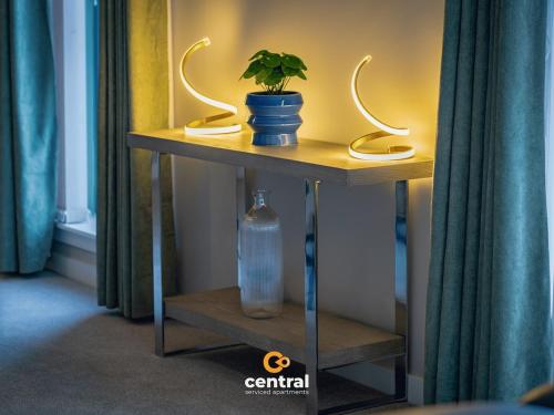 a table with a plant and a bottle on it at CENTRAL SERVICED APARTMENTS - City Quay - 2 Bedrooms - En-Suite Bathroom - Dedicated Parking Space - Fully Equipped - Walk Away From Dundee Bus & Train Station - Close to City Centre with River Views and Balcony - NEW in Dundee