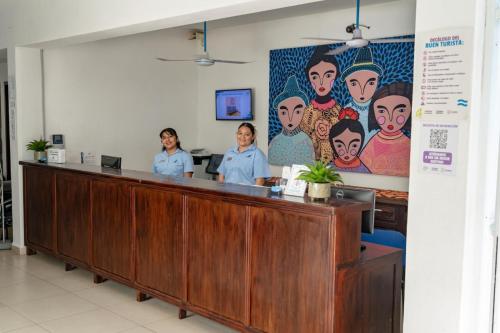 three women are standing at a reception desk in a hospital at Hotel Santa Cruz Huatulco in Santa Cruz Huatulco