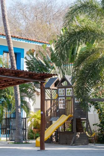 a playground with a slide and palm trees at Hotel Santa Cruz Huatulco in Santa Cruz Huatulco