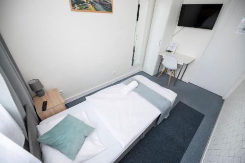 a small room with a white bed and a desk at City Place Noclegi in Wrocław