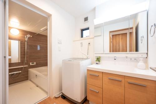 a white bathroom with a sink and a shower at Hotel Tsunagari 2 in Fukuoka