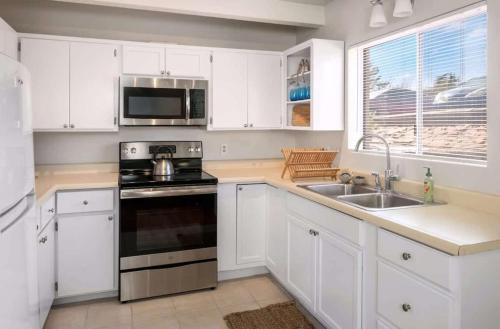 a kitchen with white cabinets and a stove and a sink at Heart of Sedona Hideaway in the Desert in Sedona