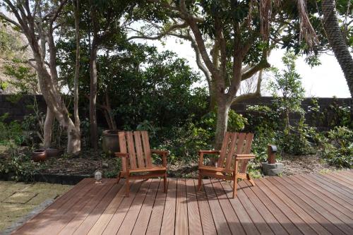 two chairs sitting on a wooden deck with trees at suo Camellia Island Inn - Vacation STAY 95452v in Oshima