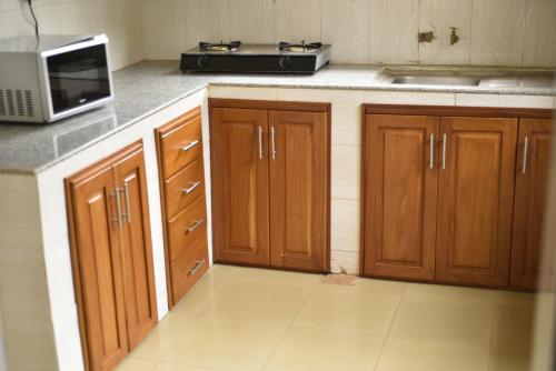 a kitchen with wooden cabinets and a microwave at Maleto's Luxury Home in Msaranga