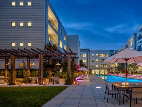 an outdoor patio with tables and umbrellas and a pool at AVE Union - Furnished Apartment, Union NJ in Union
