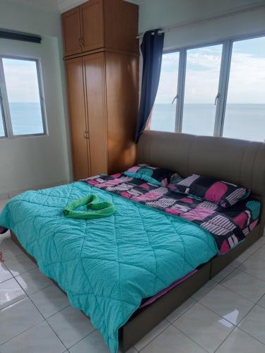 a bed with a blue comforter in a room with windows at Port Dickson Sunshine Resort in Port Dickson