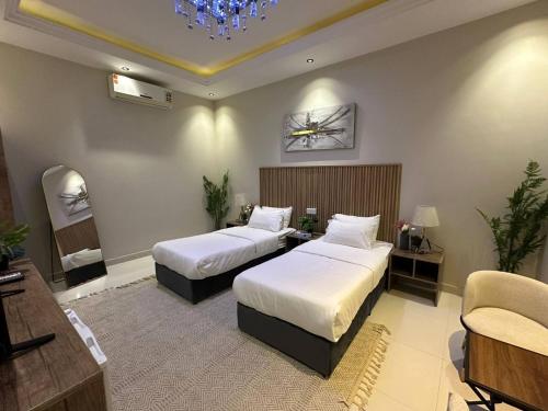 a hotel room with two beds and a chair at Nuzul R182 - Elegant Studio in Riyadh