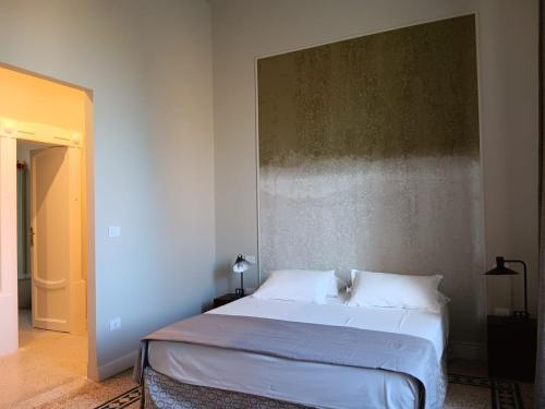 a bedroom with a white bed with a large headboard at Dimora Sant'Allegria in Lecce