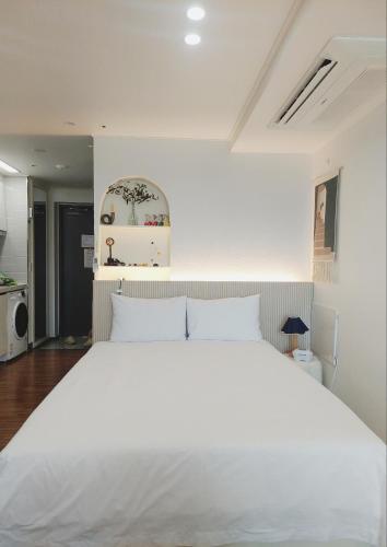 a large white bed in a white bedroom at Yeosu Ubless Gami Stay in Yeosu