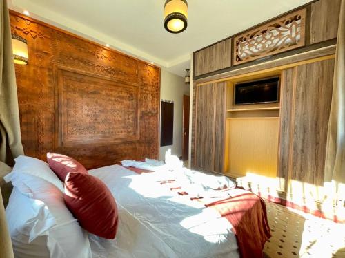 a bedroom with a large bed with a wooden headboard at Hotel Apartments Lexpert " Riad The Family" in Merzouga