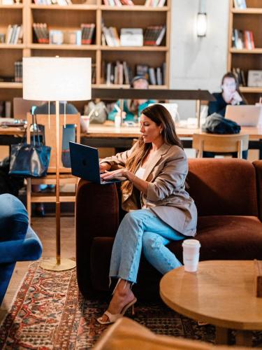 a woman sitting in a chair with a laptop at The Junto Hotel in Columbus